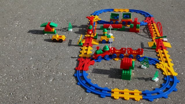 Toy station and railway on asphalt. Time lapse.