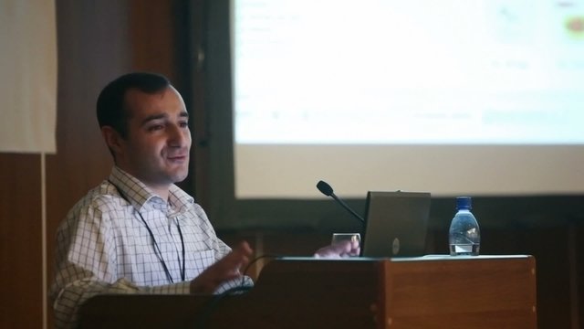 men speaking through microphone in dark conference hall