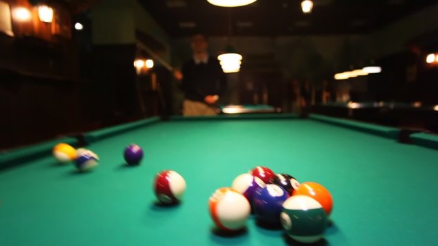 man in billiards breaks balls