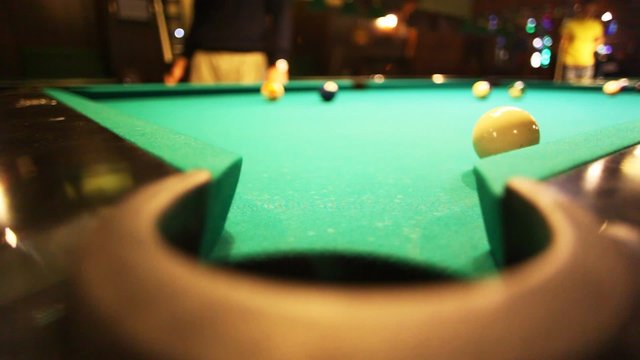 man in billiards shoots orange ball in pocket