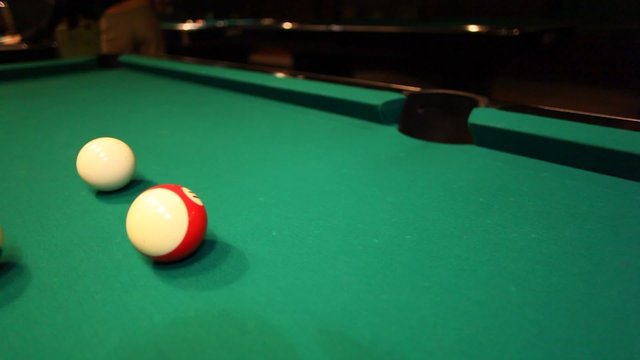 man in billiards shoots blue ball in pocket