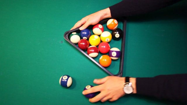 hands collect balls in triangle on biliards table