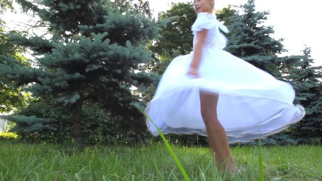 dancing girl in white dress is turned on grass
