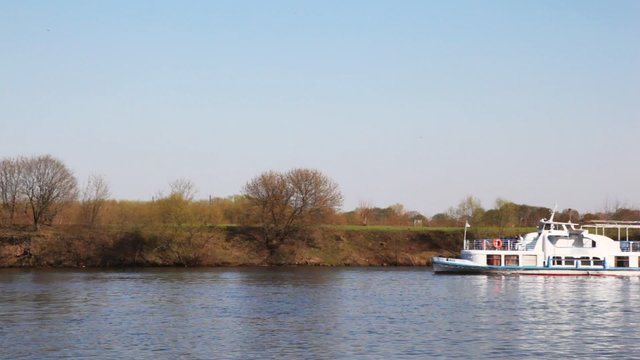 ship swims on the river against trees