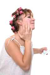 young woman in a nightgown puts a cream on the face