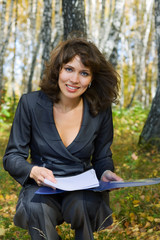 Young businesswoman with a folder on nature.