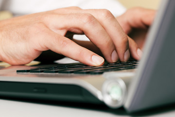 Mann schreibt auf Computertastatur