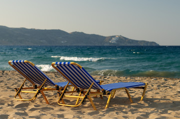 Two beachchairs in blue and white stripes on a beach