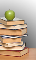 Green apple on pile of books