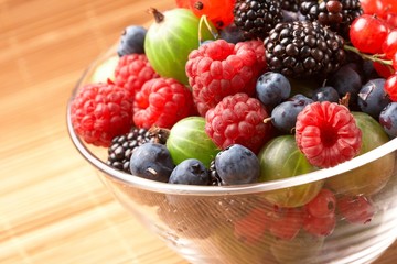 Fruit mix in the glass container, on a table from straw