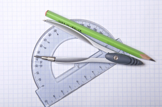 compass, protractor and pencil on copybook