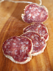 Closeup of italian typical salami and slices on wood trencher