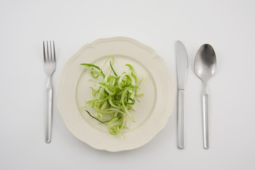 verdura su piatto con posate su sfondo bianco