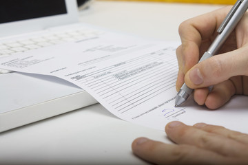 Man signing contract with white computer on background