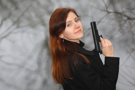 a pretty young woman aiming with the gun