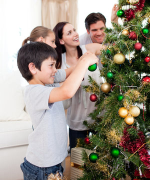 Happy family decorating a Christmas tree with boubles
