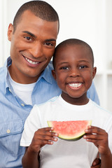 Portrait of a smiling boy eating fruit with his father