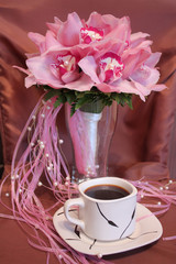 pink wedding bouquet of orchids and a cup of coffee