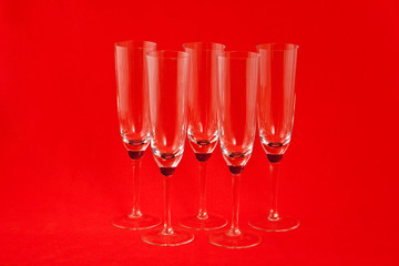 Five champagne glasses on red background