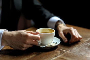 Groom's hands holding cup of coffe