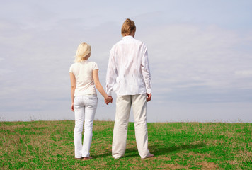 Fototapeta na wymiar Guy and girl standing on the green meadow