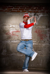 Hip hop boy dancing in modern style over grey brick wall