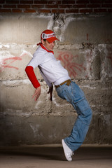 Hip hop boy dancing in modern style over grey brick wall