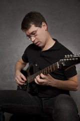 Obraz premium Man sitting and playing electric guitar