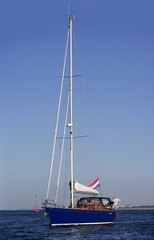 Blue sailboat on the canal sailing with engine