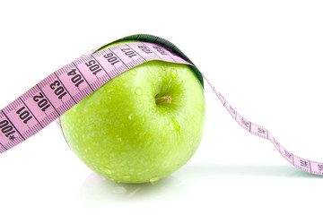 Fresh green apple with pink measure tape over white background
