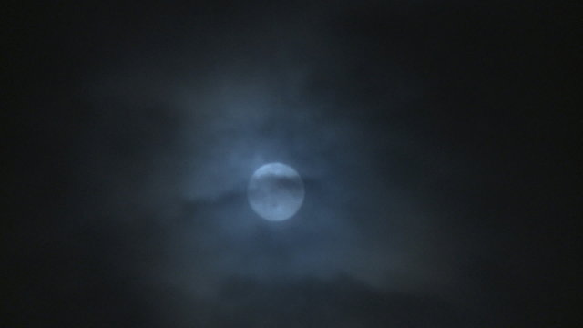 Time lapse moon rising through clouds