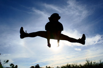 Fototapeta na wymiar Silhouette of person jumping and leg split with blue sky