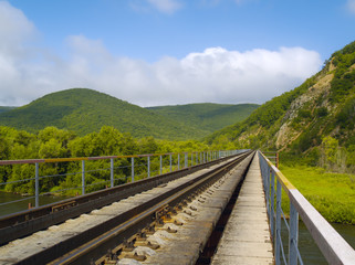Fototapeta na wymiar Year landscape with railway line, hills and cloudy sky