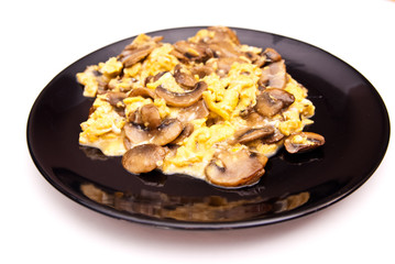 scrambled eggs with champignon mushrooms on frying pan