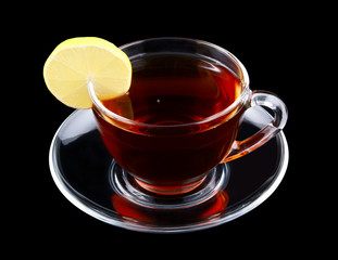 Transparent cup of tea with lemon isolated on black