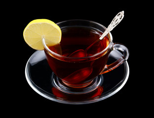 Transparent cup of tea with spoon and lemon isolated