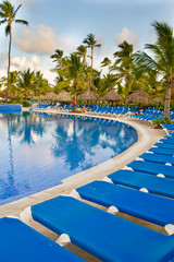 Blue and white plastic lounges around pool