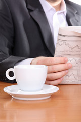 Businessman reading newspaper and drinking coffee