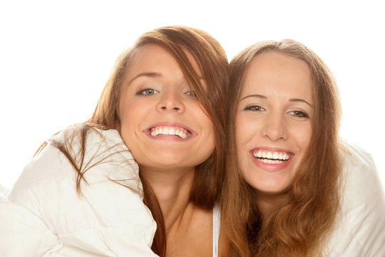 Two smiling teenage girls below duvet