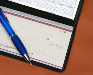 Checkbook and pen on brown leather background
