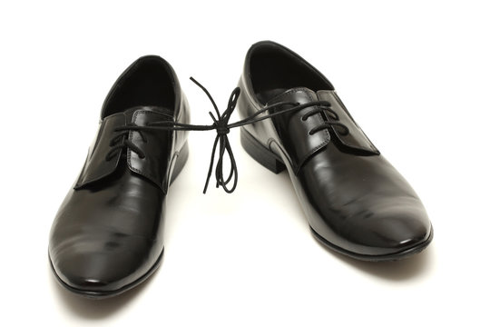 Pair of black man shoes tied together on white