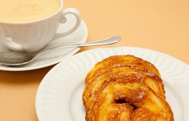 Closeup of coffee with milk in white cup and a palmier pastry