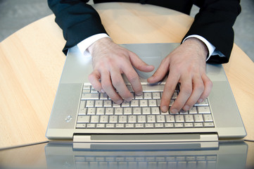 hände von manager tippen auf laptoptastatur in büro