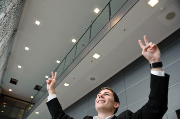 geschäftsmann steht in büro und jubelt mit victoryzeichen