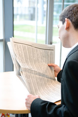geschäftsmann liest zeitung in bürogebäude,von hinten