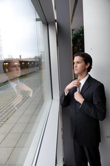 geschäftsmann kontrolliert krawatte in spiegelnder scheibe