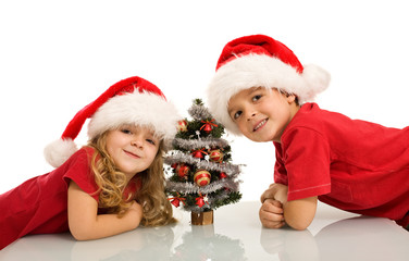 Happy kids with santa hats and small christmas tree