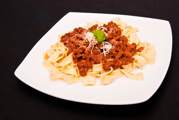 spaghetti bolognese with cheese on white plate
