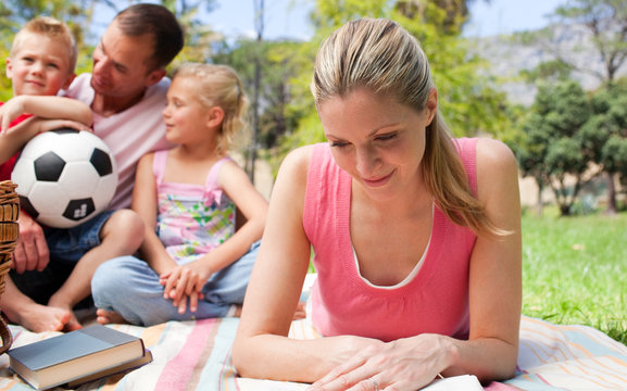 Concentrated mother reading at a picnic with her family