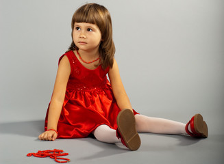 Cute little girl in a red dress sitting